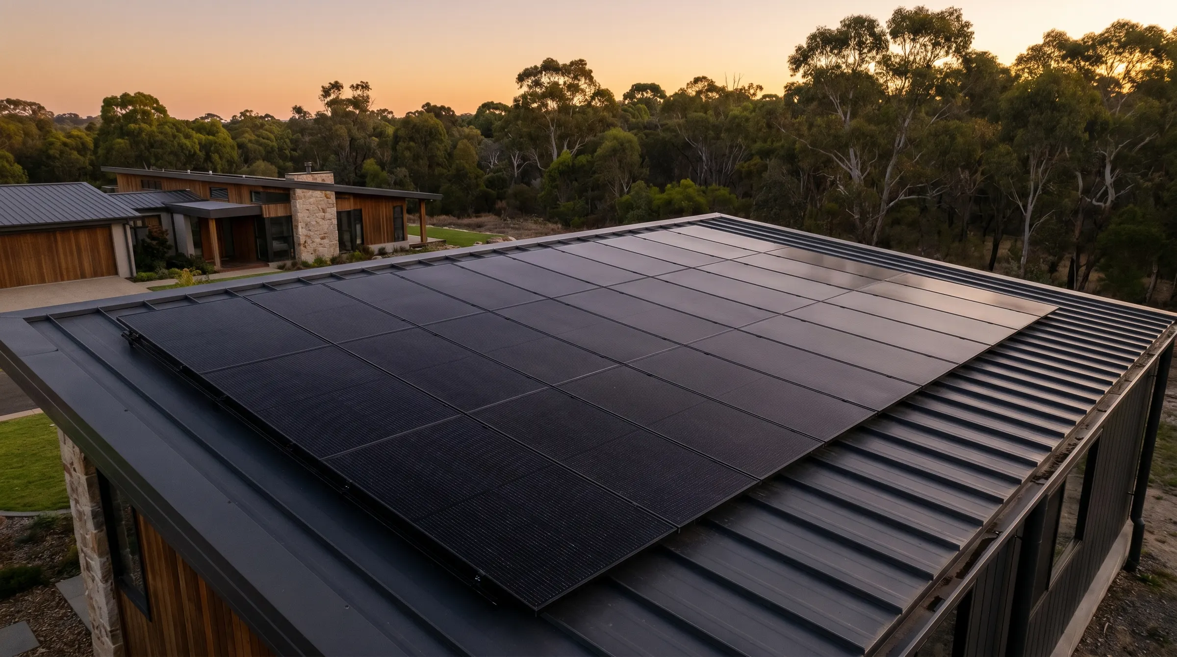 Clean all-black solar array flush on a dark roof, Canberra bushland beyond at dusk